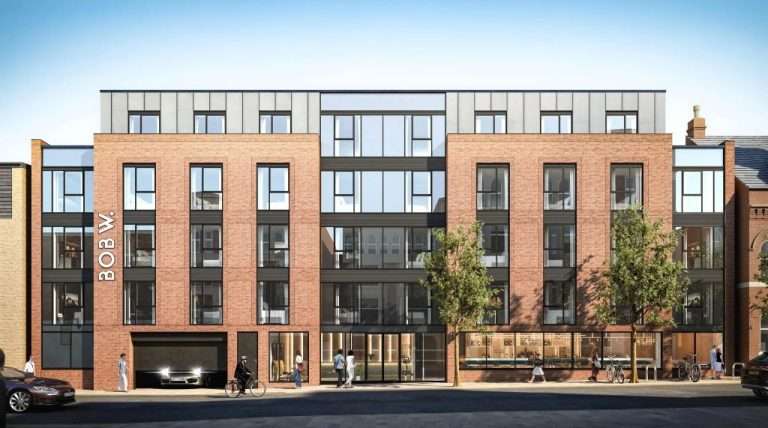 Modern brick-and-glass apartment building with large windows and ground-floor shops on a city street, pedestrians nearby.