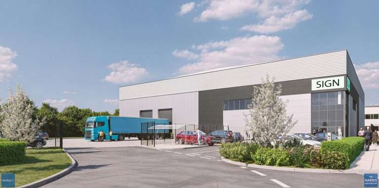 Modern industrial building with a large SIGN sign, a blue delivery truck, cars, and people in the parking area on a sunny day.